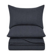 A dark navy blue bedding set featuring a pillowcase, a folded sheet or duvet cover, and a matching folded pillow, all with a subtle textured chevron pattern, shown against a plain white background.